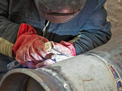 welder performs welding works on pipelines stainless steel